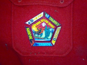 National Outdoor Badges. The location/order of the segments around the central patch does not matter. The emblem is shown centered on the right pocket of the red jac-shirt (personal comment: the emblem looks the best on the jac-shirt)